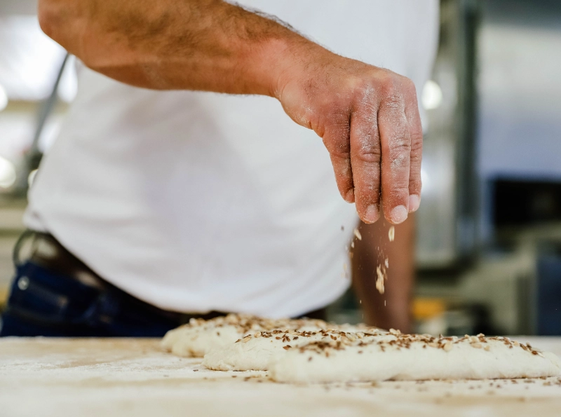 Bäcker bei der Herstellung frischer Backwaren in der Backstube der Bäckerei Weindl